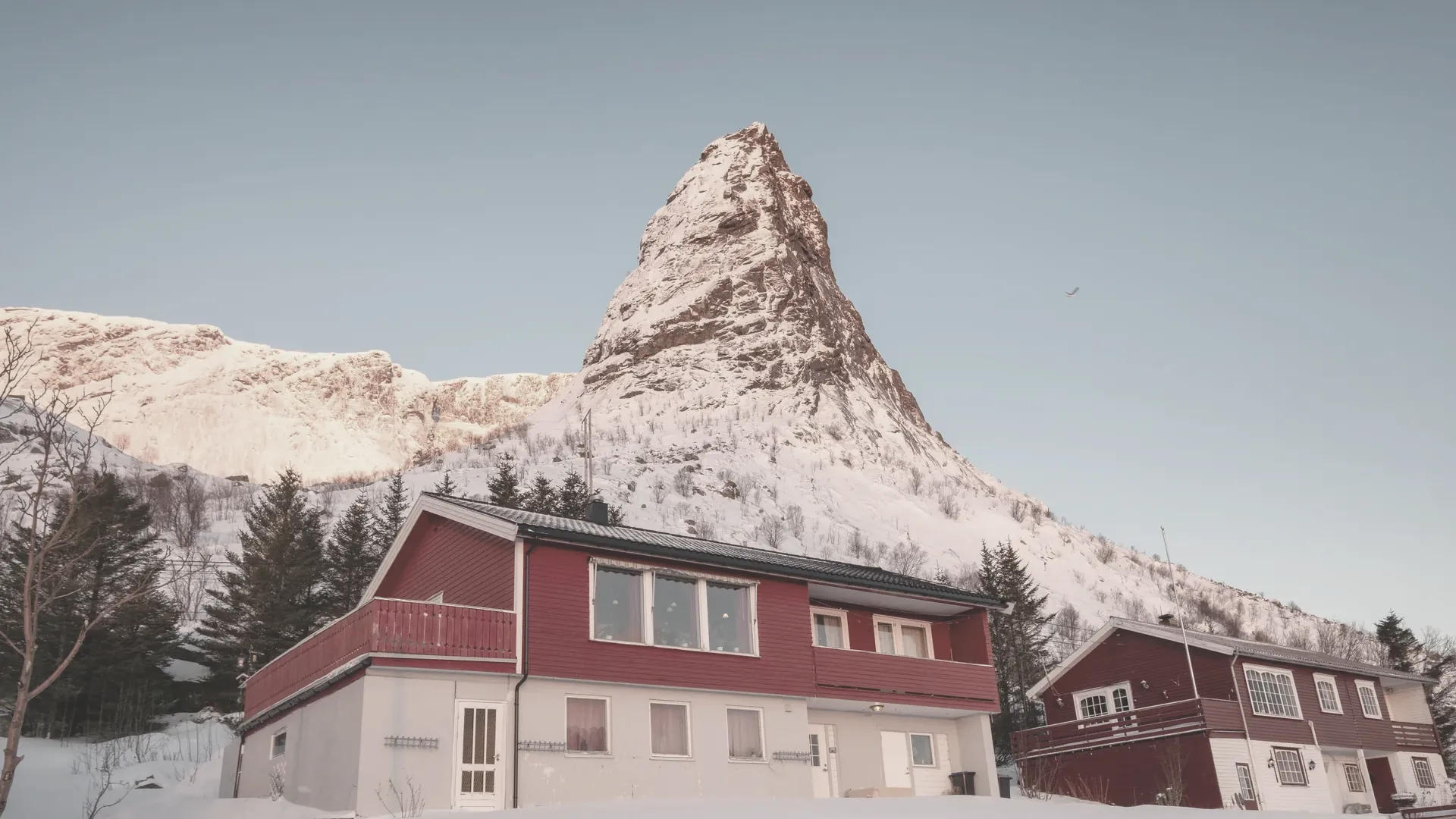 Sonnenaufgang über einem verschneiten Berg oberhalb eines Dorfes