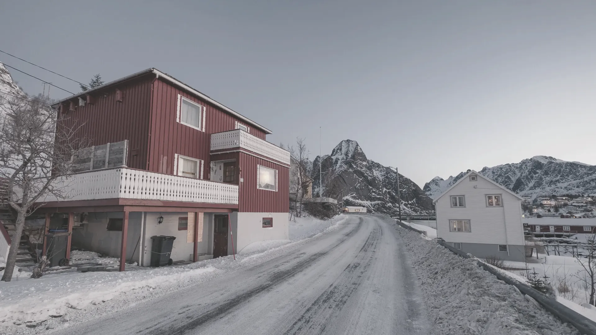 Ein rotes Haus vor einem verschneiten Berg an einer stillen Bucht