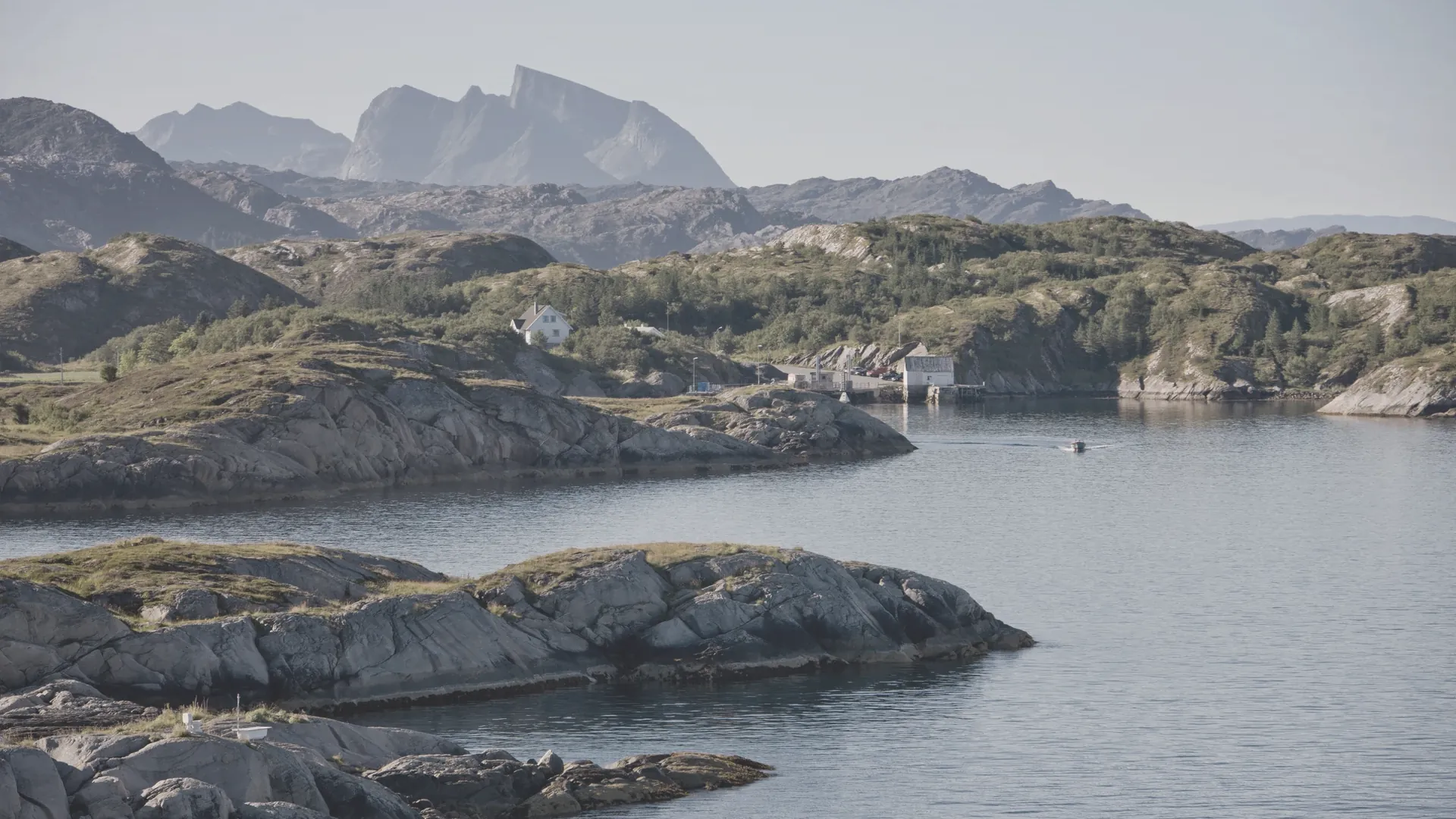 Eine weite Fjordlandschaft mit flachen Felsinseln unter hohem Himmel