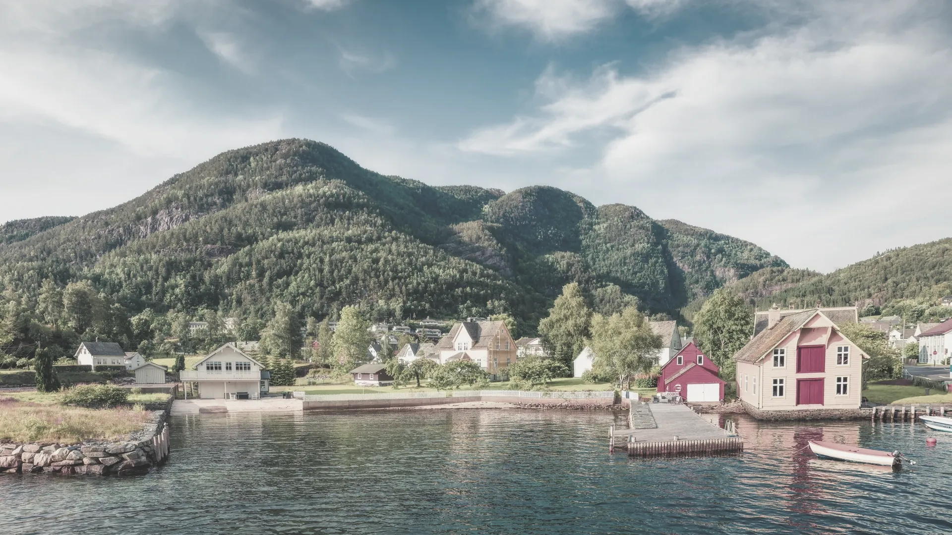 Ein sommerlicher Blick über ein Dorf am Fjord mit grünen Hängen