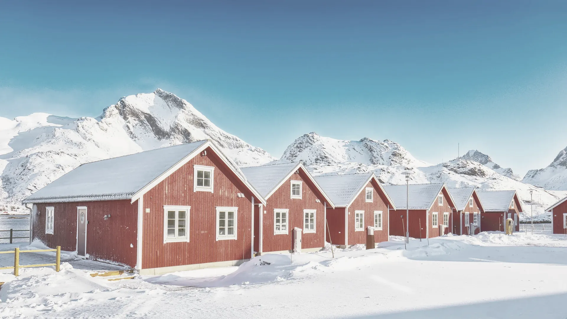 Verschneite Holzhäuser an einer Küste im weichen Winterlicht